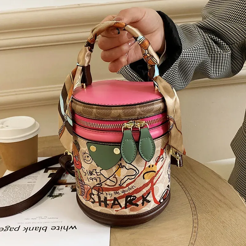 T10383B9146_113342.webp Women Fashion Bear Doodle Cylinder Bag - Image 1